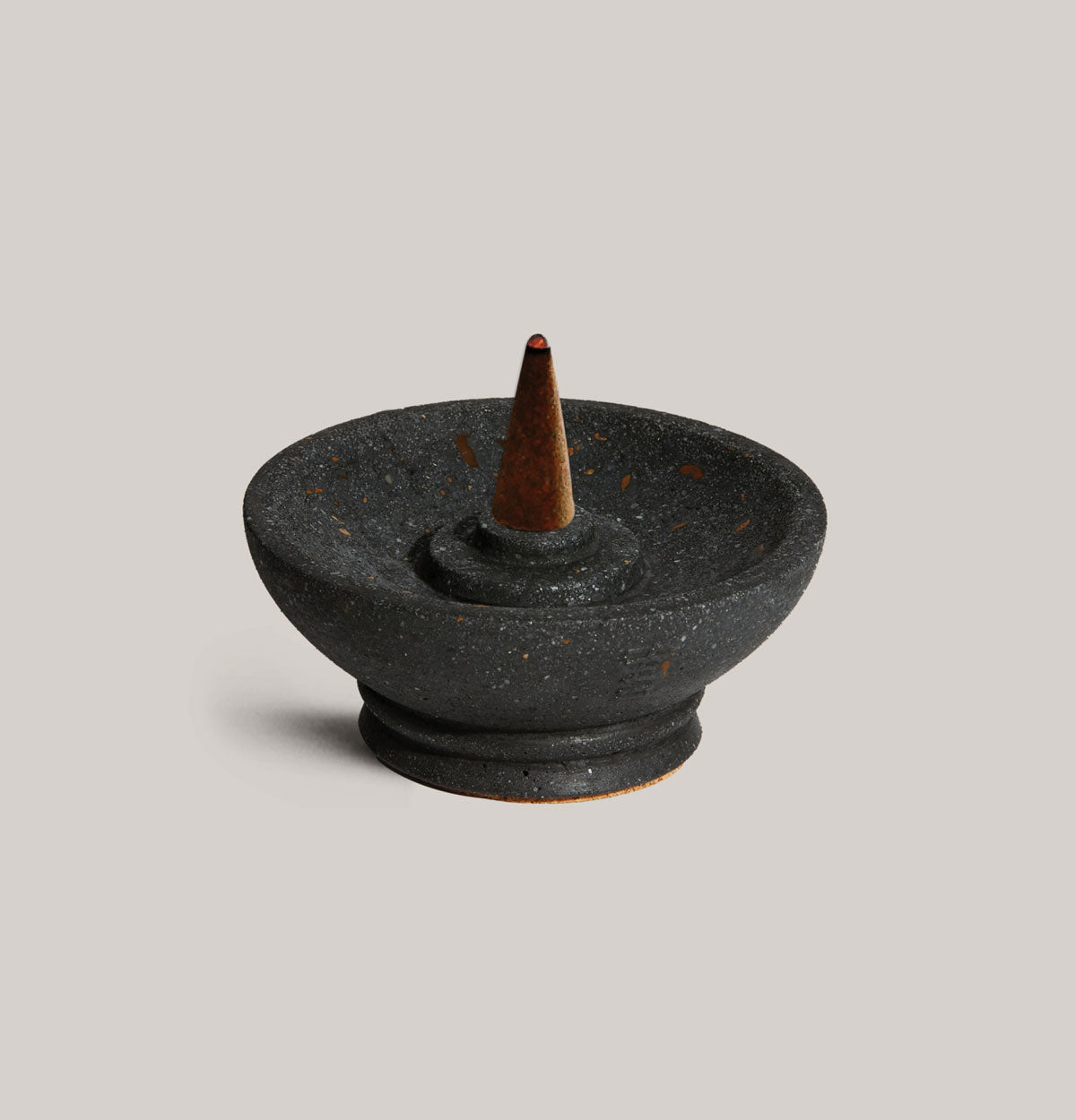 Black ceramic incense burner with a cone on a light gray background