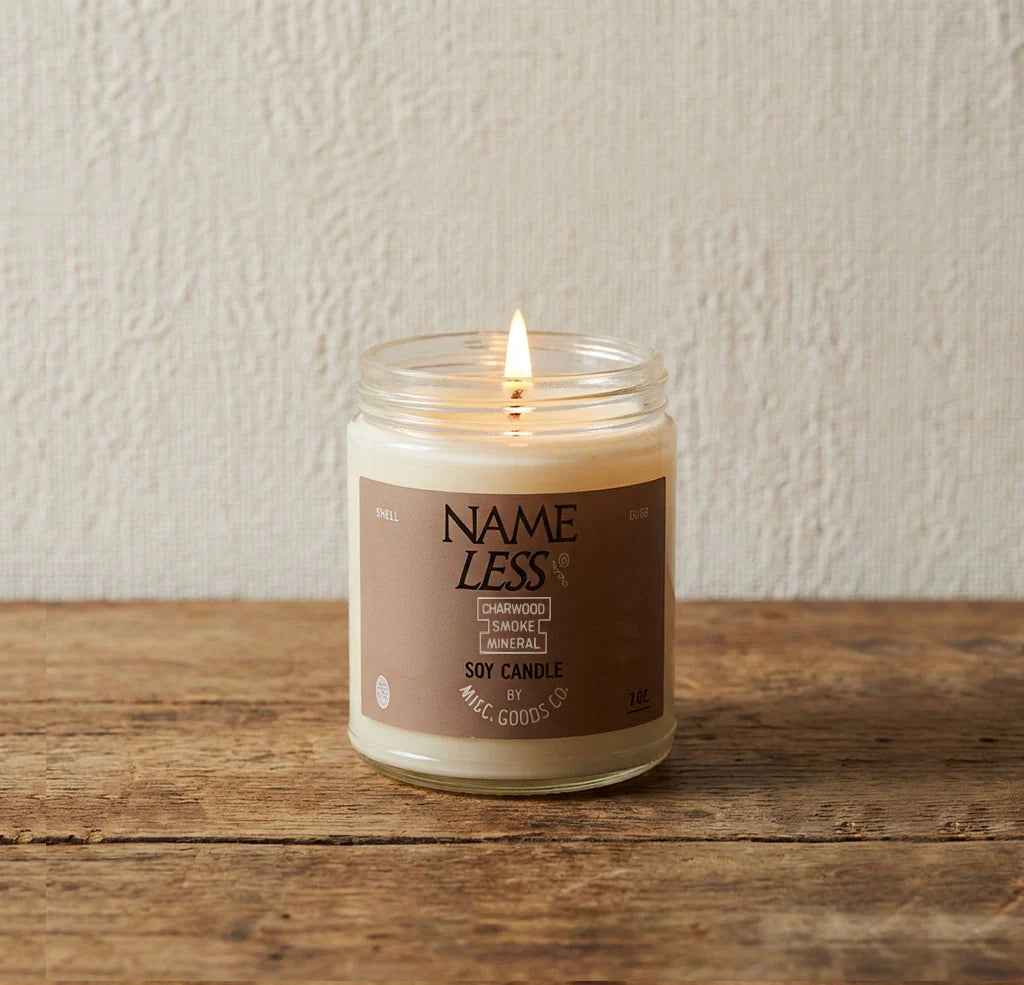 Candle in a glass jar with a label on a wooden surface and light background