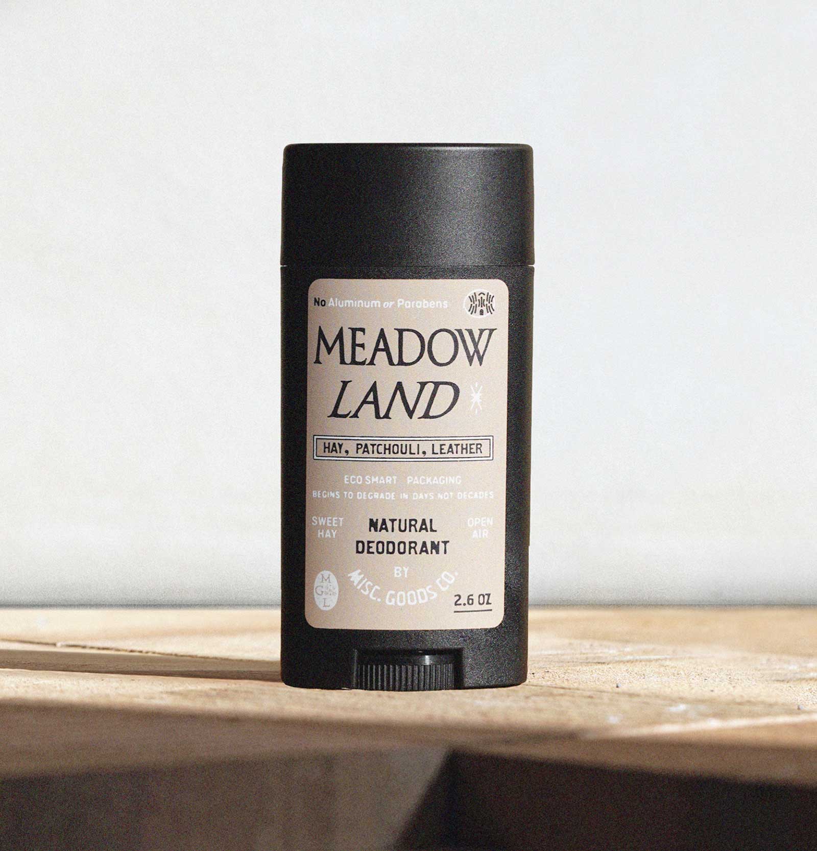 Meadow Land deodorant stick on a wooden surface with a light gray background