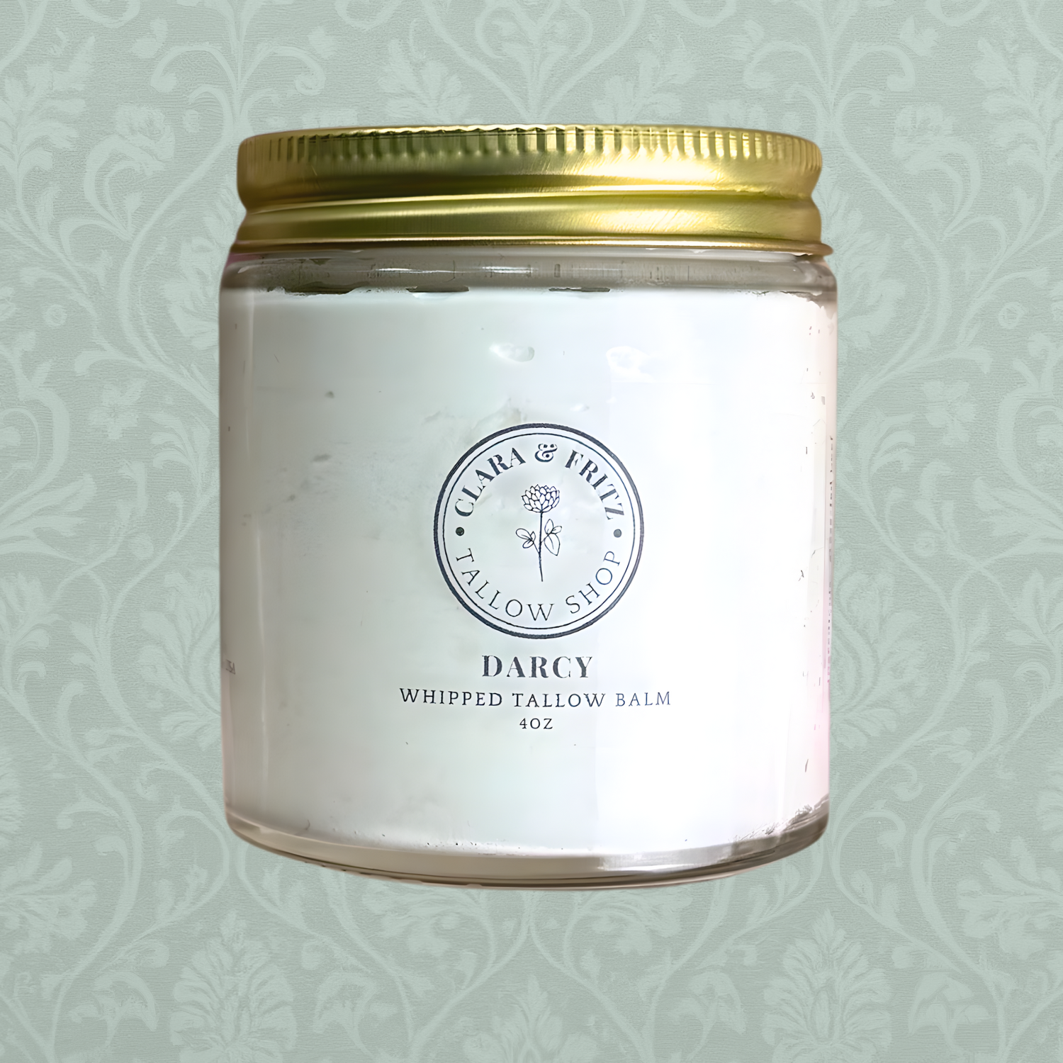 Whipped tallow balm jar with gold lid on a light green patterned background