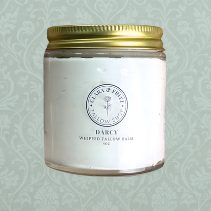 Whipped tallow balm jar with gold lid on a light green patterned background