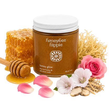 Jar of honeybee hippie honey with honeycomb, flowers, and a honey dipper on a white background