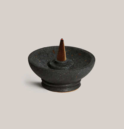 Black ceramic incense burner with a single cone on a light gray background